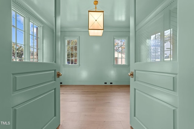 doorway to outside featuring baseboards, light wood-style floors, and crown molding