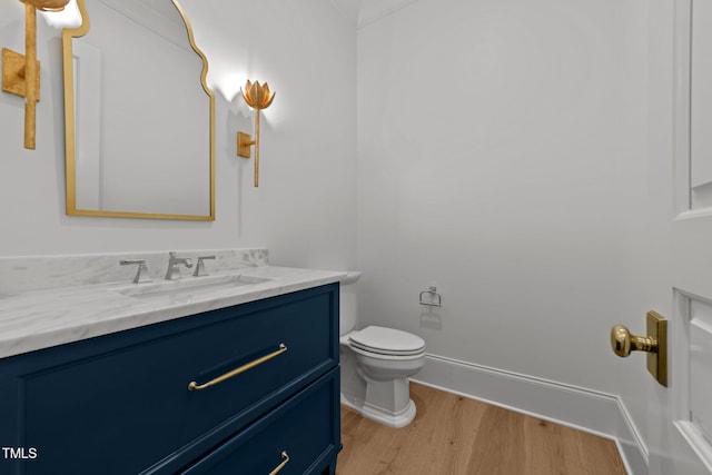 bathroom featuring toilet, vanity, crown molding, and hardwood / wood-style floors