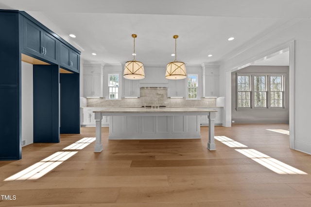 kitchen featuring blue cabinets, tasteful backsplash, a kitchen bar, and light wood-style flooring