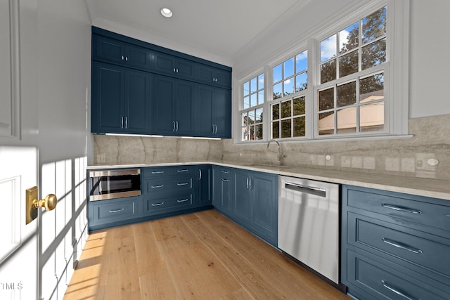 kitchen featuring light hardwood / wood-style floors, decorative backsplash, sink, appliances with stainless steel finishes, and blue cabinets