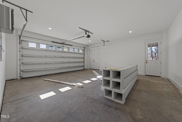 garage with a garage door opener, recessed lighting, and baseboards