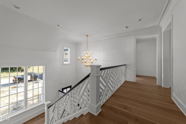 corridor with baseboards, ornamental molding, wood finished floors, an inviting chandelier, and an upstairs landing