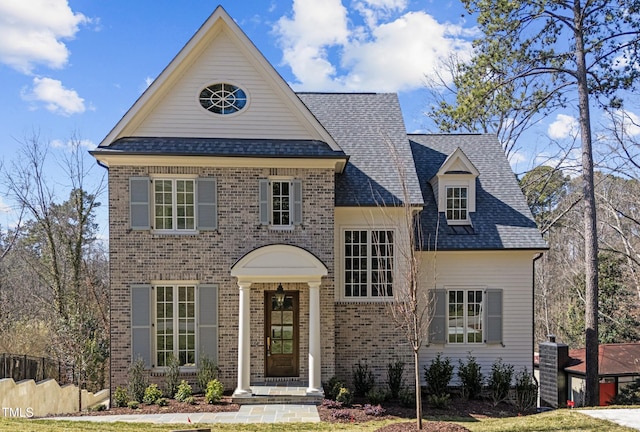 view of front of property featuring a shingled roof and brick siding