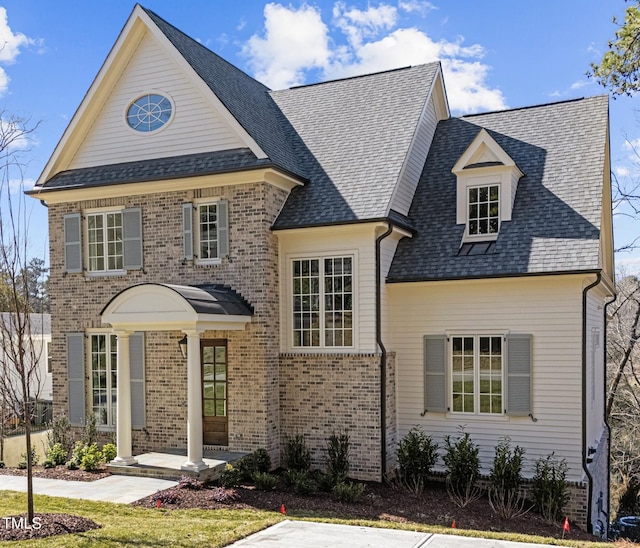 view of front of house with brick siding and a shingled roof