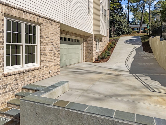 view of home's exterior featuring driveway, an attached garage, and brick siding