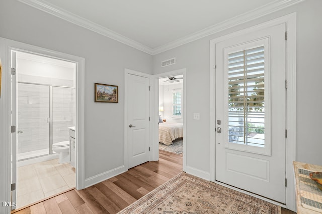 foyer with light hardwood / wood-style flooring, ornamental molding, and ceiling fan