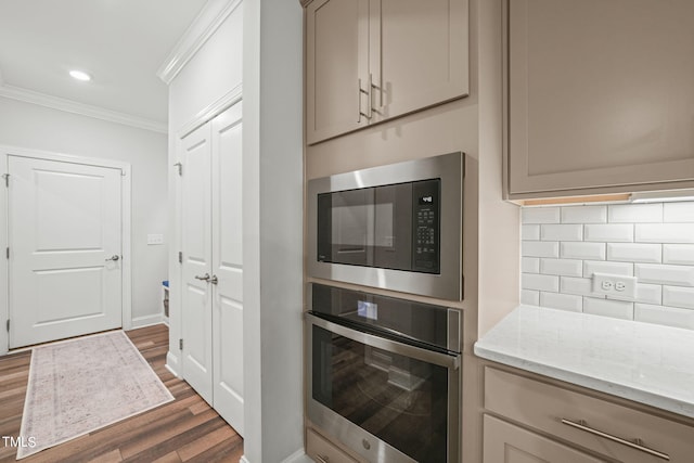 kitchen with crown molding, dark wood-type flooring, stainless steel appliances, light stone counters, and tasteful backsplash