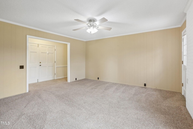 carpeted empty room with ceiling fan, a textured ceiling, and ornamental molding