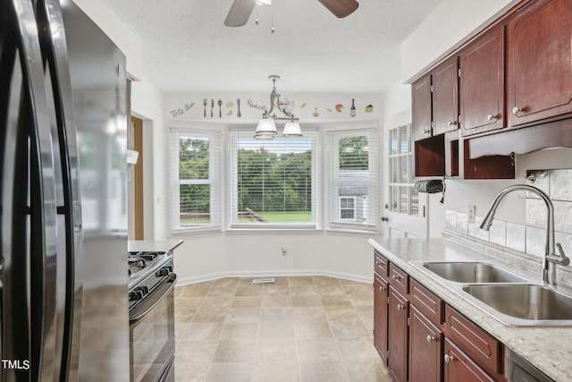 kitchen featuring a textured ceiling, hanging light fixtures, sink, and stainless steel appliances