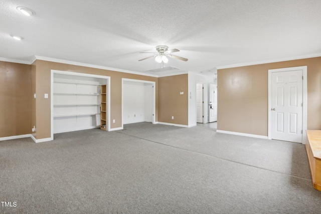 unfurnished bedroom featuring a textured ceiling, carpet flooring, multiple closets, ornamental molding, and ceiling fan