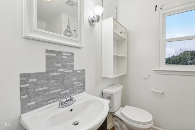 bathroom with decorative backsplash, sink, plenty of natural light, and toilet