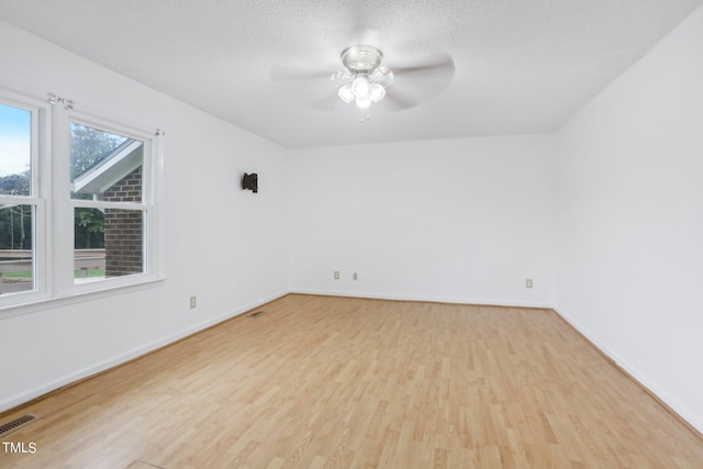 empty room with a textured ceiling, ceiling fan, and light hardwood / wood-style flooring