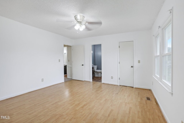 unfurnished bedroom featuring ceiling fan, connected bathroom, a textured ceiling, light hardwood / wood-style flooring, and a closet