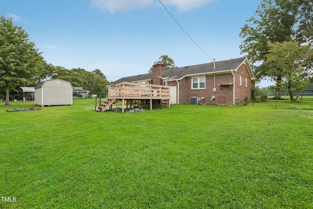 rear view of house with a wooden deck, cooling unit, a storage shed, and a lawn