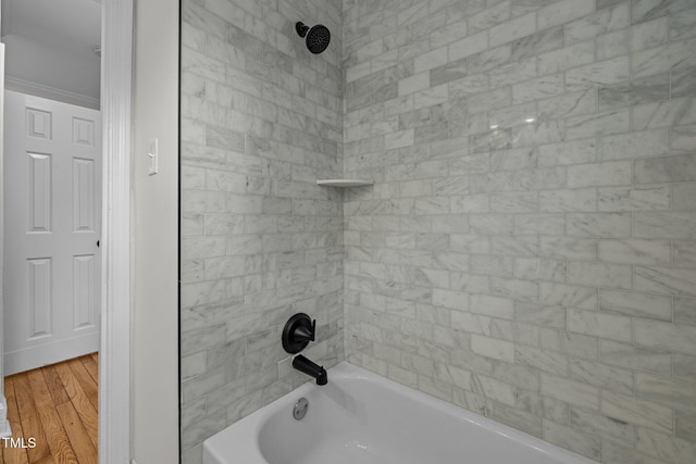 bathroom featuring wood-type flooring and tiled shower / bath