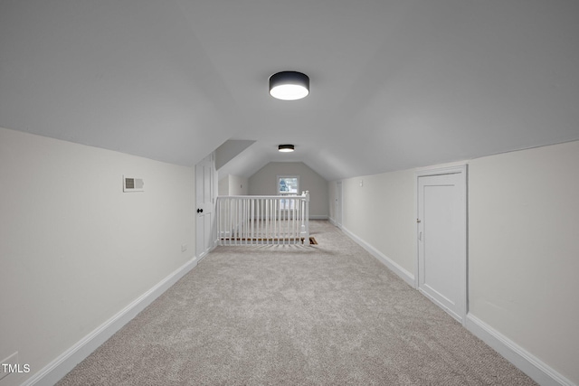 bonus room with light carpet and vaulted ceiling