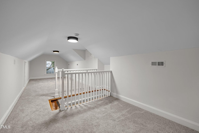 bonus room with light colored carpet and vaulted ceiling