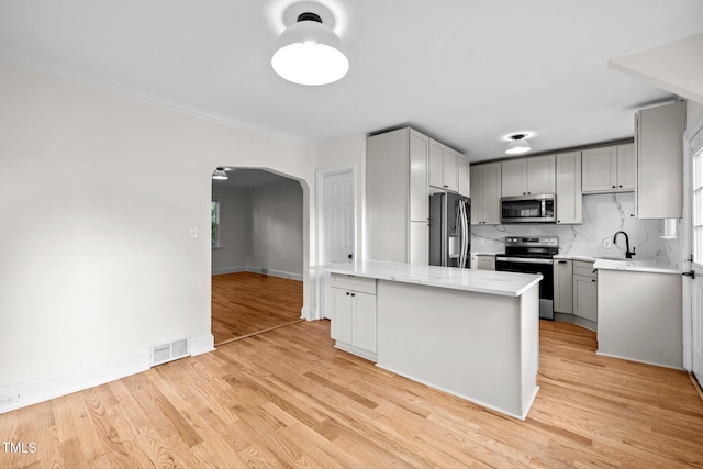 kitchen with gray cabinetry, appliances with stainless steel finishes, and light hardwood / wood-style floors