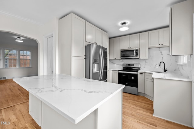 kitchen featuring stainless steel appliances, sink, light wood-type flooring, and a kitchen island