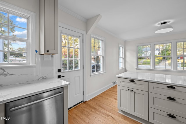 kitchen with stainless steel dishwasher, light stone counters, ornamental molding, and light wood-type flooring