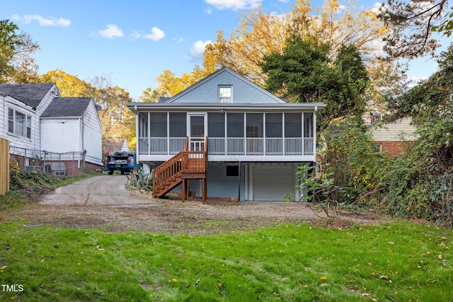 back of house featuring a garage, a lawn, and a sunroom