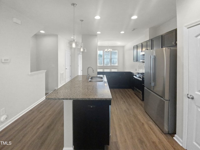 kitchen featuring light stone counters, sink, a center island with sink, appliances with stainless steel finishes, and dark hardwood / wood-style flooring