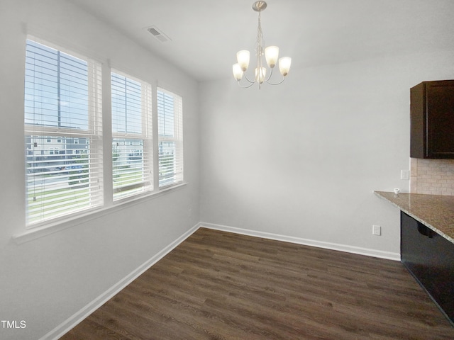 unfurnished dining area with a chandelier and dark hardwood / wood-style flooring