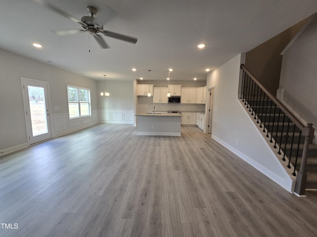 unfurnished living room with ceiling fan, sink, and light hardwood / wood-style floors