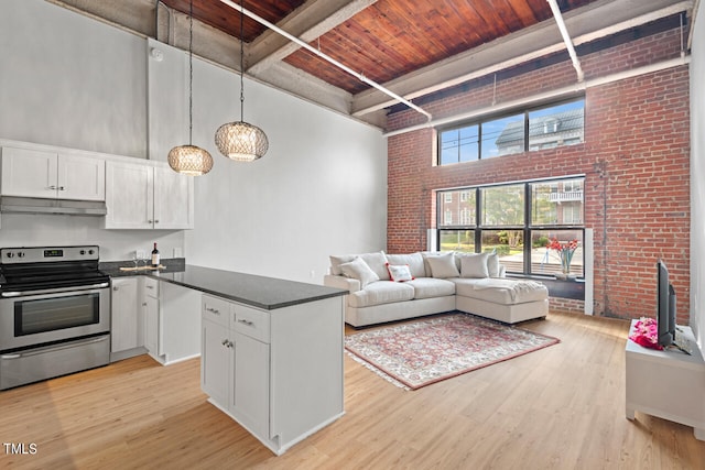 living room with brick wall, wood ceiling, light wood-type flooring, and a towering ceiling