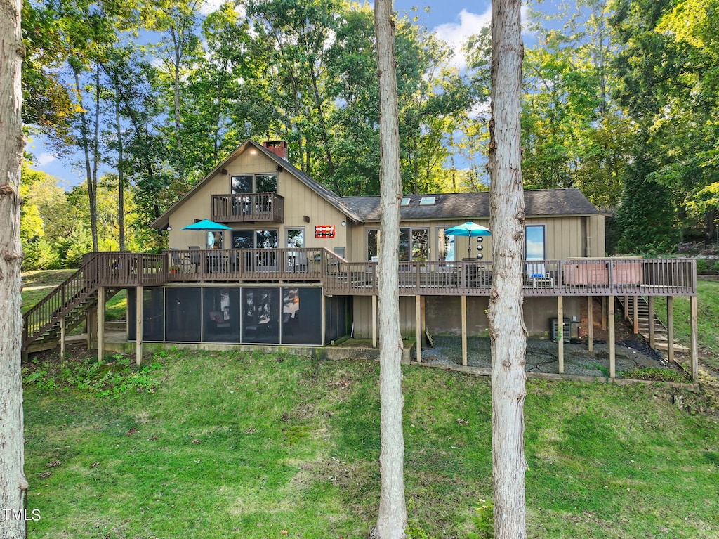 rear view of property featuring a lawn, a deck, and central AC unit