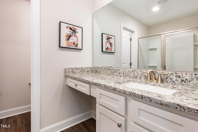 bathroom featuring wood-type flooring, a shower with shower door, and vanity