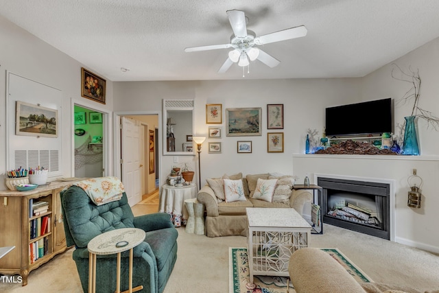 living room featuring ceiling fan, light colored carpet, and a textured ceiling