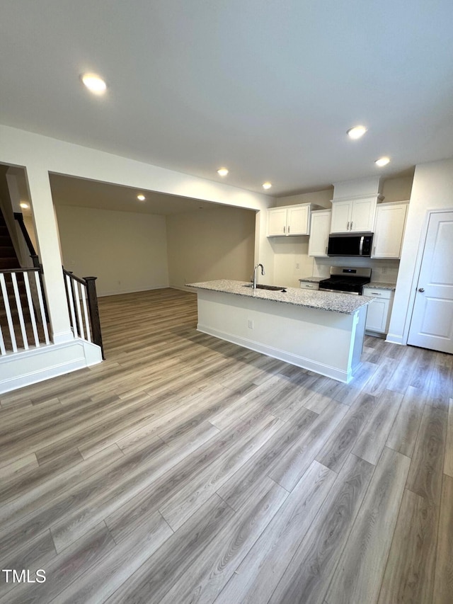 kitchen featuring white cabinetry, stainless steel gas stove, light stone counters, and light hardwood / wood-style floors