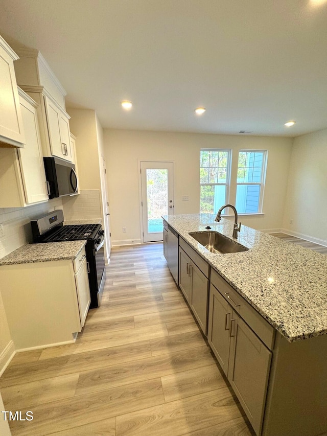 kitchen featuring backsplash, a spacious island, sink, light stone counters, and stainless steel appliances