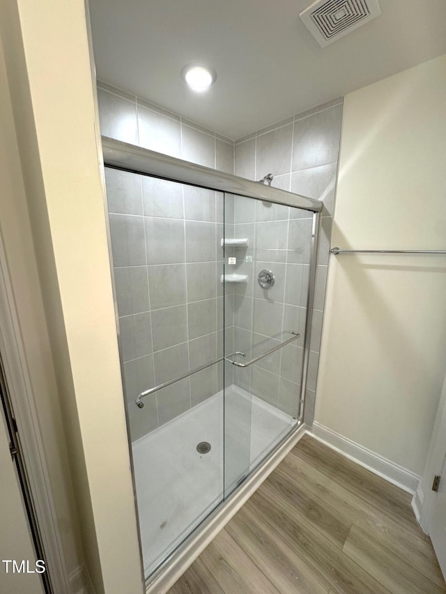 bathroom featuring wood-type flooring and a shower with door