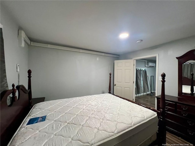 bedroom featuring wood-type flooring, a walk in closet, and a wall mounted air conditioner