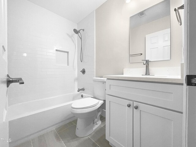 full bathroom with tile patterned floors, tiled shower / bath combo, vanity, and toilet