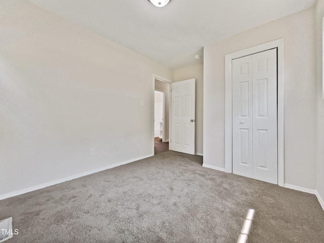 unfurnished bedroom featuring dark carpet and a closet