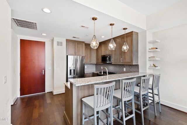 kitchen with dark wood-type flooring, tasteful backsplash, kitchen peninsula, hanging light fixtures, and stainless steel appliances