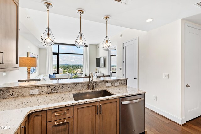 kitchen featuring light stone counters, sink, decorative light fixtures, dark hardwood / wood-style flooring, and stainless steel dishwasher