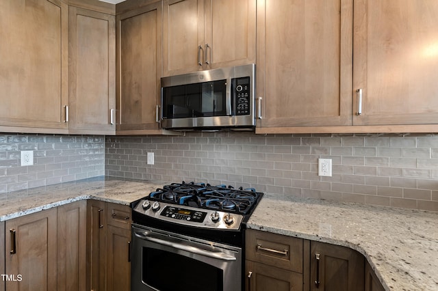 kitchen with light stone countertops, stainless steel appliances, and tasteful backsplash