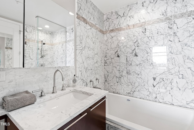 bathroom with tile walls, vanity, and tiled shower / bath