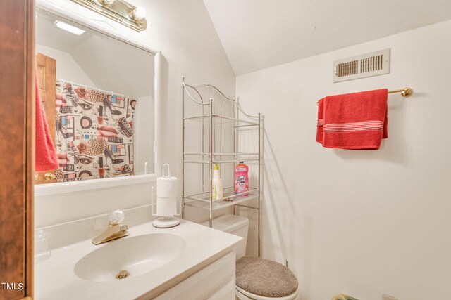 bathroom featuring vanity, vaulted ceiling, and toilet