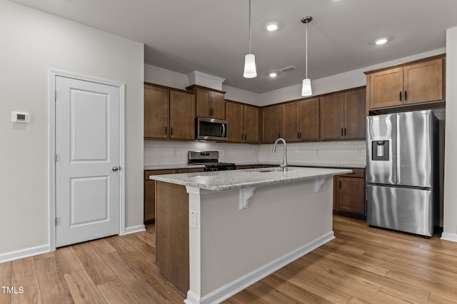 kitchen featuring light stone counters, stainless steel appliances, sink, and light hardwood / wood-style floors