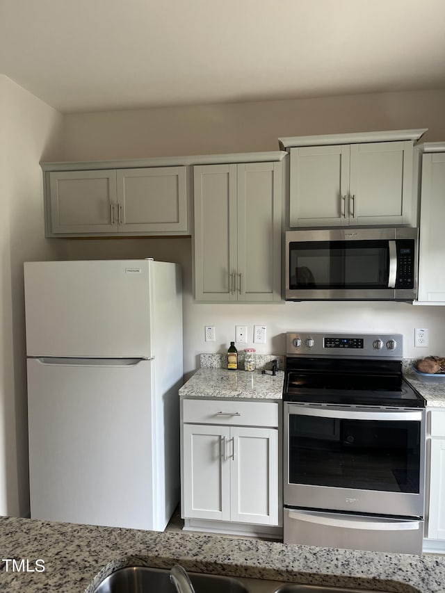 kitchen featuring stainless steel appliances and light stone counters