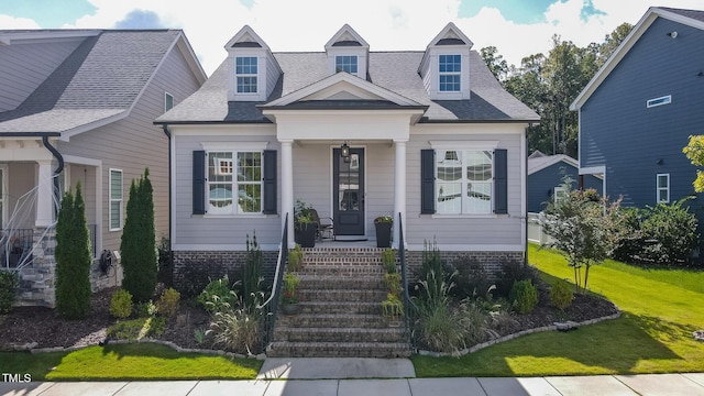 cape cod home with a shingled roof and a front lawn