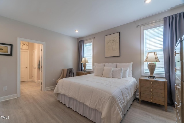 bedroom with recessed lighting, connected bathroom, light wood-style flooring, and baseboards