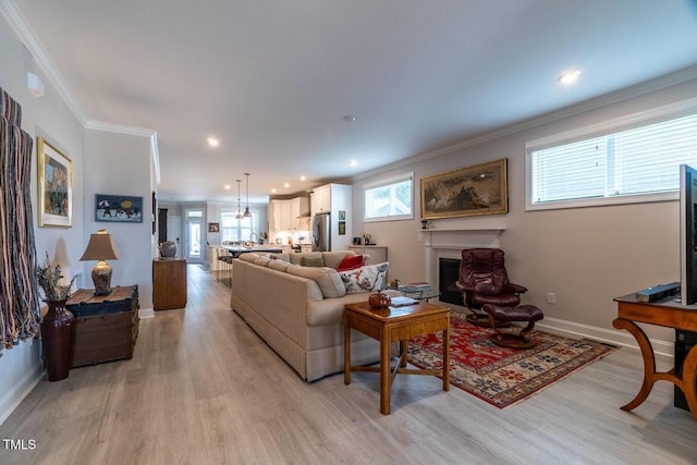 living room with plenty of natural light, light hardwood / wood-style floors, and ornamental molding