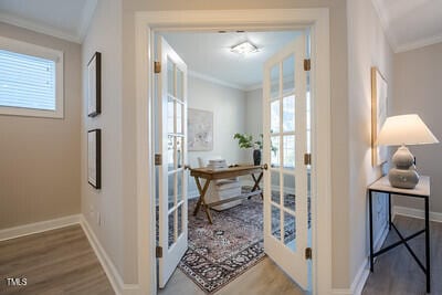 interior space with ornamental molding, french doors, wood finished floors, and baseboards