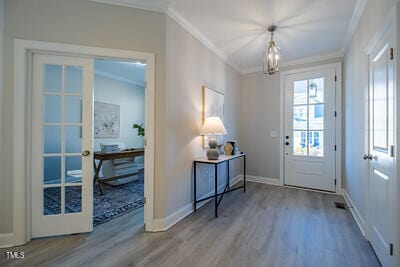 doorway to outside with french doors, crown molding, baseboards, and wood finished floors